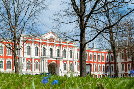 Jelgavas pils pavasarī. Tālumā redzama pils, tuvplānā zied zili ziedi.