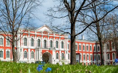 Jelgavas pils pavasarī. Tālumā redzama pils, tuvplānā zied zili ziedi.